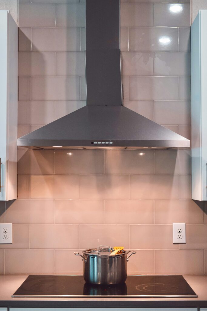 Hizmetlerimiz A contemporary kitchen scene featuring a stainless steel exhaust hood and a pot on the stove.